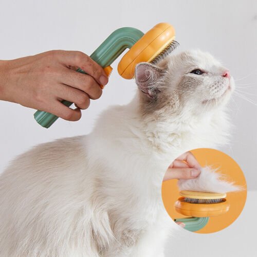 Self-cleaning slicker brush with orange head and green handle, grooming a cat